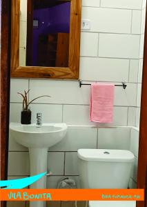 a bathroom with a sink and a toilet and a mirror at Casinhas Vila Bonita Hobbit in Baía Formosa