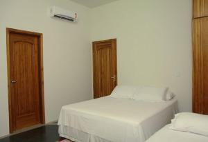 1 dormitorio con 2 camas y puerta de madera en Eco Pousada Sinimbu, en Cáceres