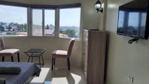 Habitación con cama, TV y mesa. en Avana Hills Boracay Prime Panoramic Suite, en Boracay