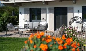 a patio with chairs and flowers in front of a house at Hof Hauserbichl in Fischbachau