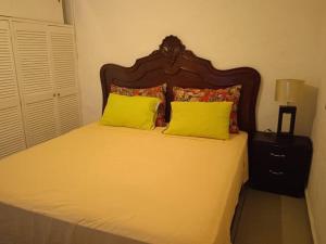een slaapkamer met een bed met 2 gele kussens bij Departamento los Mangos in Puerto Vallarta