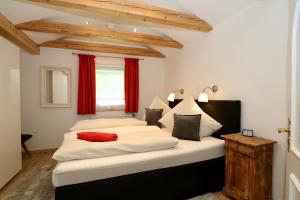 a bedroom with two white beds with red curtains at Alpengold in Garmisch-Partenkirchen