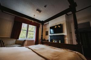 a bedroom with a bed and a tv and a window at Brook Hall Hotel in Childer Thornton