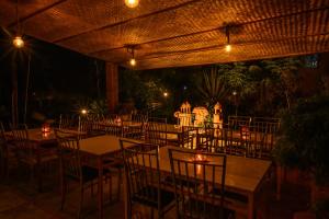 un restaurante con mesas y sillas por la noche en Anandavana Jungle Resort By Lexstays - Kanthalloor-Marayur en Kanthalloor