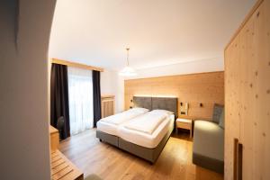 - une chambre avec un grand lit et un canapé dans l'établissement Hotel Ortler, à Castelrotto