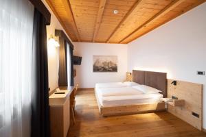 a bedroom with a bed and a desk at Hotel Ortler in Castelrotto