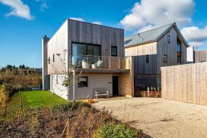a contemporary house with a wooden facade and a fence at Family friendly property in nature reserve The Hangout ML15 in Somerford Keynes