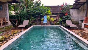 a swimming pool with a fountain in a yard at Gusti Home Stay Ubud in Ubud