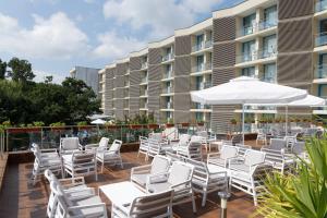 a deck with white chairs and umbrellas in front of a building at Hotel Slavey - All Inclusive in Golden Sands