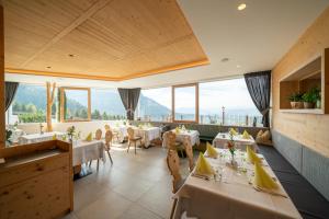 un ristorante con tavoli, sedie e ampie finestre di Hotel Ortler a Castelrotto