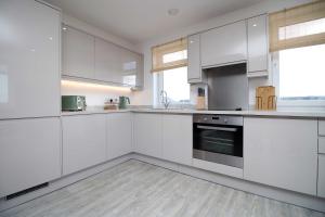 a white kitchen with white cabinets and appliances at Stylish modern retreat overlooking Poole Quay in Poole