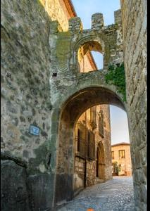 um antigo edifício de pedra com um arco numa rua em las llaves del arca em Trujillo