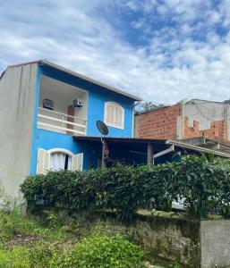 a blue house with a window and a brick building at Bela casa em condominio de frente a cachoeira in Paraty