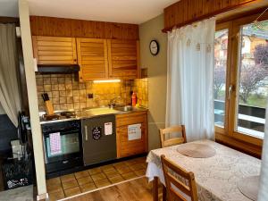 a kitchen with a table and a sink and a stove at Charmant Studio, 2 adultes , Centre de Nendaz in Nendaz