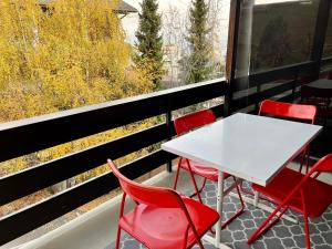 a table and red chairs on a balcony with a view at Charmant Studio, 2 adultes , Centre de Nendaz in Nendaz