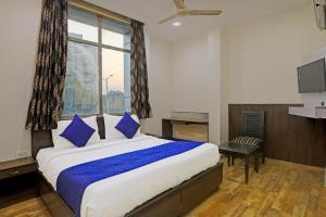 a bedroom with a bed with blue pillows and a window at Hotel Grand Tushar - Near Ghaziabad Railway Station in Ghaziabad