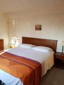 サン・ヴィート・ロ・カーポにあるCasa Rosalbaのベッドルーム1室(大型ベッド1台、木製ヘッドボード付)