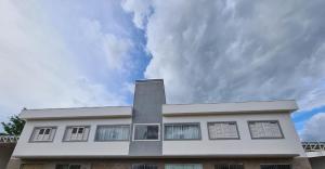 un edificio blanco con un cielo nublado en el fondo en Terra Home Suítes 2 - Hospedagens de alto padrão em Piumhi MG, en Piauí