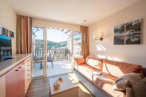 een woonkamer met een bank en een balkon bij Village Pierre & Vacances Cap Esterel - Saint Raphaël Village in Agay - Saint Raphael