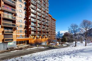 ein hohes Gebäude im Schnee mit einer Straße in der Unterkunft Aux Rêveries des Cimes - Vostok Zodiaque in Villarembert
