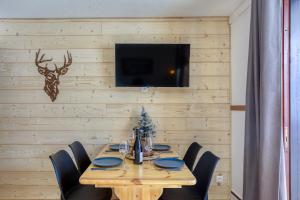 einen Holztisch mit schwarzen Stühlen und einen TV an der Wand in der Unterkunft Aux Rêveries des Cimes - Vostok Zodiaque in Villarembert
