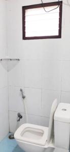 a white bathroom with a toilet and a window at Grass dew in Yercaud