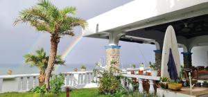 a rainbow over a house with a surfboard and palm trees at shanedel's inn & café in Basco