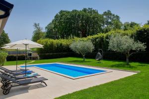 una piscina con dos tumbonas y una sombrilla en VILLA GIOVANNA POREC, en Poreč