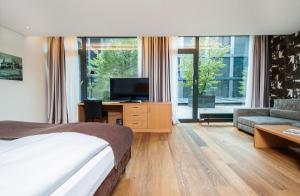 a bedroom with a bed and a tv and a couch at Tailormade Hotel SIHLPARK Schindellegi in Schindellegi