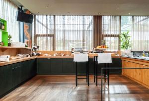 une cuisine avec des placards vert foncé et des tabourets blancs dans l'établissement Tailormade Hotel SIHLPARK Schindellegi, à Schindellegi