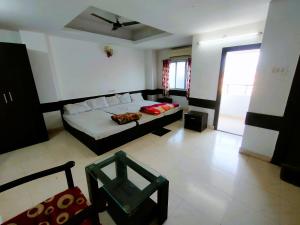 een woonkamer met een bed en een raam bij STAYMAKER Chakra Nayan Tara Sonu Inn in Tarapith