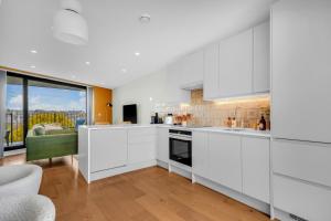 a kitchen with white cabinets and a large window at Be London - The London Residences in London