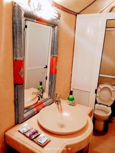 a bathroom with a sink and a toilet and a mirror at Magic Luxury Camp in Merzouga
