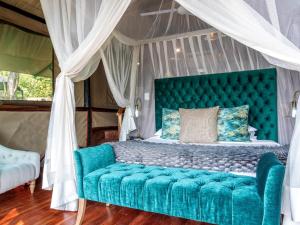 - une chambre avec un lit turquoise à baldaquin dans l'établissement Tintswalo Siankaba, à Livingstone