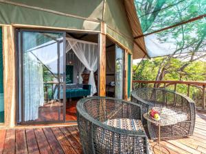 a screened in porch with wicker chairs on a wooden deck at Tintswalo Siankaba in Livingstone