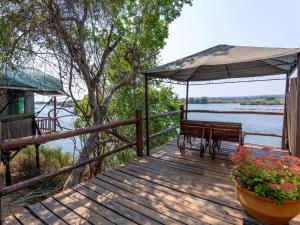una terraza de madera con un banco y una sombrilla en Tintswalo Siankaba en Livingstone