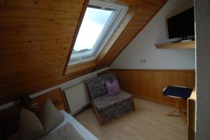 Cette chambre mansardée comprend une chaise et une fenêtre. dans l'établissement Gästehaus Balzer, à Marbourg