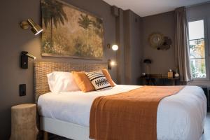 a bedroom with a large bed with orange pillows at Hôtel Le Patio - Deauville in Deauville