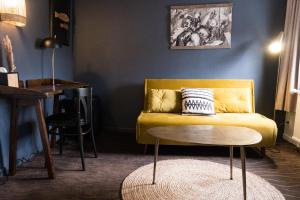 a living room with a yellow couch and a table at Hôtel Le Patio - Deauville in Deauville