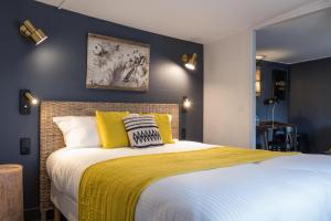 a bedroom with a large bed with yellow pillows at Hôtel Le Patio - Deauville in Deauville
