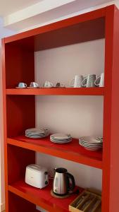 estante rojo con platos y tetera en LC Apartamentos César Augusto, en Zaragoza