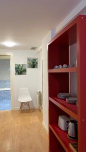 a red book shelf in a room with a white chair at LC Apartamentos César Augusto in Zaragoza