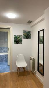 Cette chambre comprend une chaise blanche et un miroir. dans l'établissement LC Apartamentos César Augusto, à Saragosse