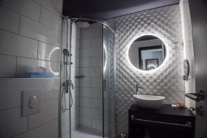 ein Bad mit einem Waschbecken und einer Dusche mit einem Spiegel in der Unterkunft Hotel Palatinus in Sopron