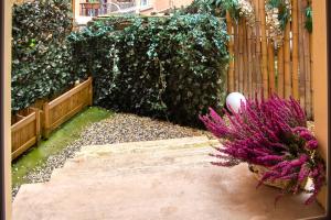 een tuin met een hek en paarse bloemen bij Catone District Hotel in Rome