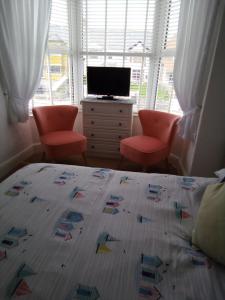 a bedroom with a bed and two chairs and a television at Applebys Guest House in Holyhead