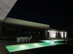 a swimming pool at night with white tables and chairs at Luxury House del Delta in Deltebre