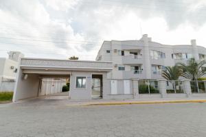 un gran edificio blanco con un cartel delante en Apto 02 quartos Praia de Bombas, en Bombinhas