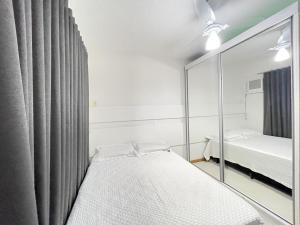 1 dormitorio con espejo junto a la cama en Apto 02 quartos Praia de Bombas, en Bombinhas