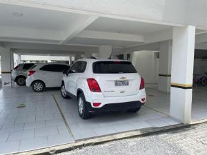 un coche blanco aparcado en un estacionamiento en Apto 02 quartos Praia de Bombas, en Bombinhas